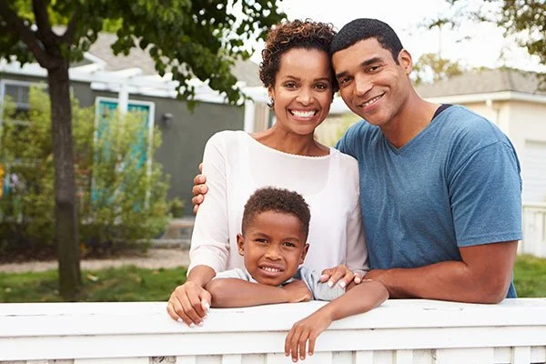 family standing by a wooden vinyl aluminum fence around a house