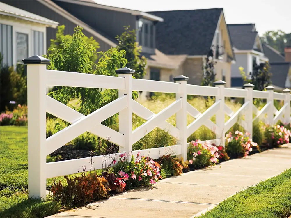 White decorative residential fence with landscaped flower beds